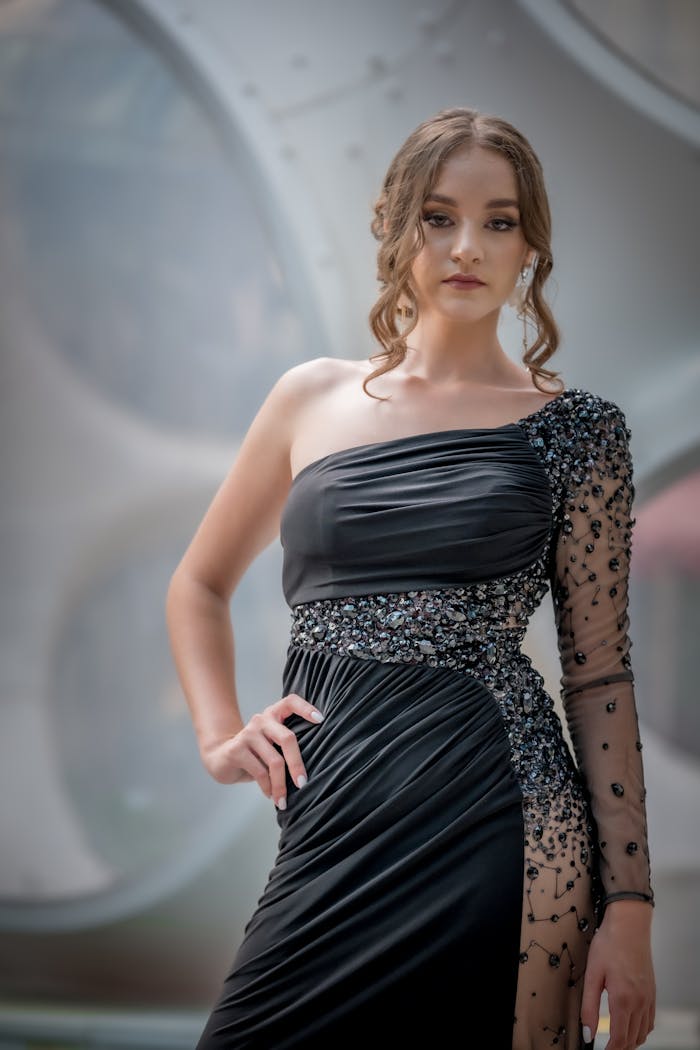 Elegant woman in a black designer gown with decorative detailing, captured outdoors.